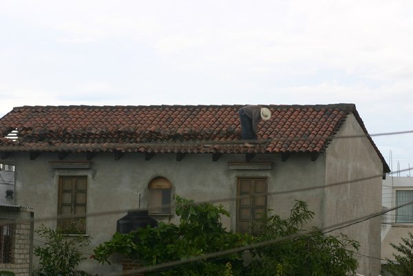 A neighbor repairs his tile roof