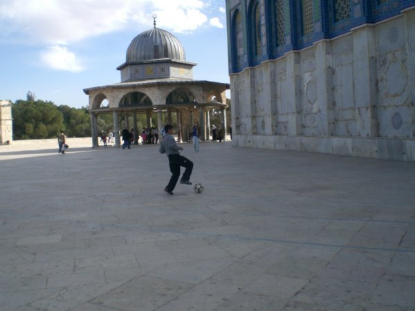 Little boy playing soccer next to the Dome.