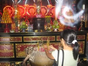 Tam prays and places her incense in the pot 