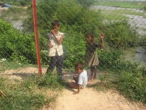 Local kids beg for money and one crawls under the fence to get closer to us