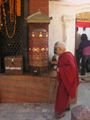 a monk spins the prayer wheel to rid his sins