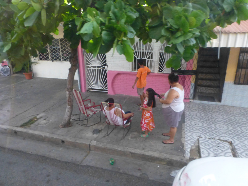 6. Family resting and doing hair in front of their home