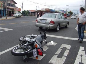 Typical Costa Rica accident: motorcycle attempted illegal high-speed pass on right but got caught when car attempted legal right turn into parking lot.