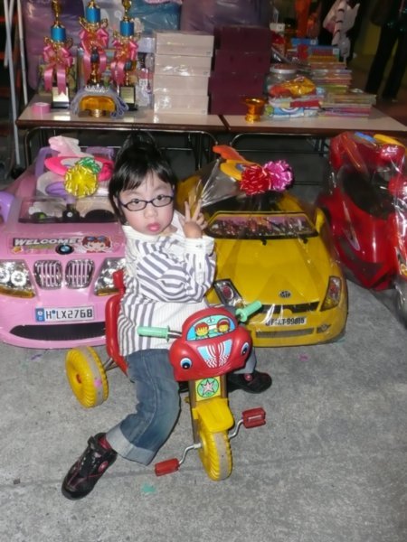 One of my kinders posing on his trike, in front of some of the raffle prizes