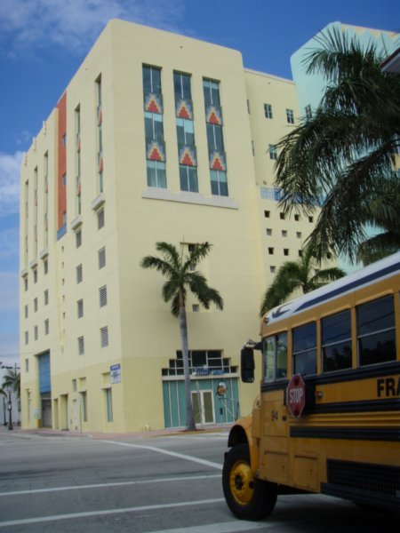 Art deco building, palm trees and American schoolbus