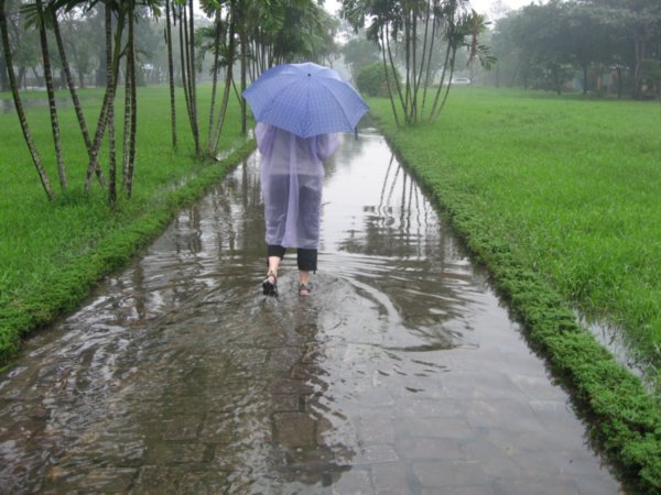 Wading along a path in a stylish poncho and umbrella combination