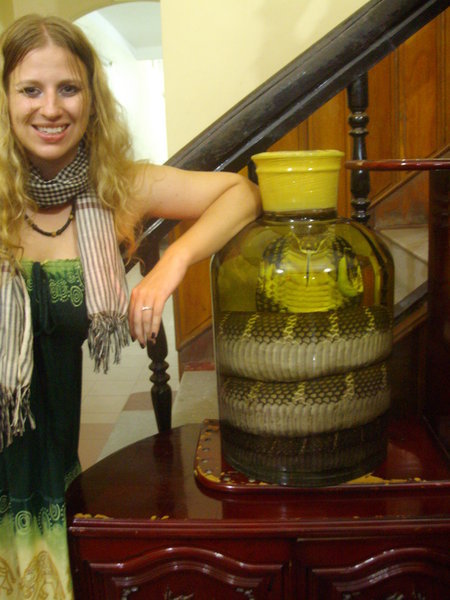 Amy next to a bottle of rice wine with a king cobra in it